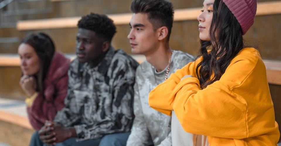 A group of diverse young adults sitting on steps, showcasing friendship.